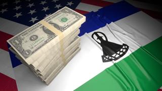 Lesotho National Flag, American dollars and flag placed on top of the American flag