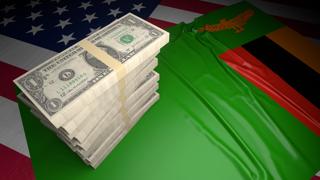 Zambia National Flag, American dollars and flag placed on top of the American flag