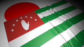 Abkhazia National Flag, The national flag placed on top of the Japanese flag on a desk in a dark space