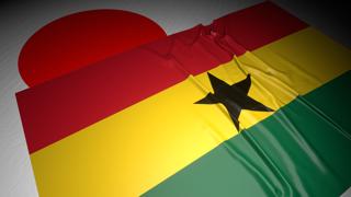 Ghana National Flag, The national flag placed on top of the Japanese flag on a desk in a dark space