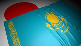 Kazakhstan National Flag, The national flag placed on top of the Japanese flag on a desk in a dark space