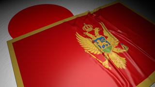 Montenegro National Flag, The national flag placed on top of the Japanese flag on a desk in a dark space