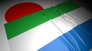 Sierra-Leone National Flag, The national flag placed on top of the Japanese flag on a desk in a dark space