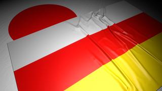 South-Ossetia National Flag, The national flag placed on top of the Japanese flag on a desk in a dark space