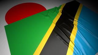 Tanzania National Flag, The national flag placed on top of the Japanese flag on a desk in a dark space