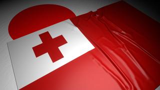 Tonga National Flag, The national flag placed on top of the Japanese flag on a desk in a dark space