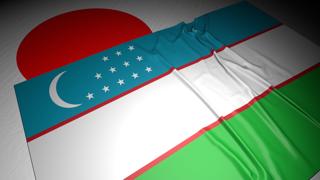 Uzbekistan National Flag, The national flag placed on top of the Japanese flag on a desk in a dark space