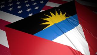 Antigua-and-Barbuda National Flag, A flag placed on top of an American flag on a desk in a dark space