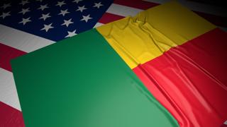 Benin National Flag, A flag placed on top of an American flag on a desk in a dark space