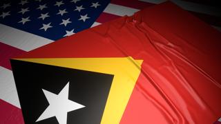 East-Timor National Flag, A flag placed on top of an American flag on a desk in a dark space