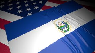 El-Salvador National Flag, A flag placed on top of an American flag on a desk in a dark space