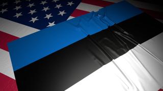 Estonia National Flag, A flag placed on top of an American flag on a desk in a dark space