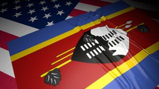 Eswatini National Flag, A flag placed on top of an American flag on a desk in a dark space