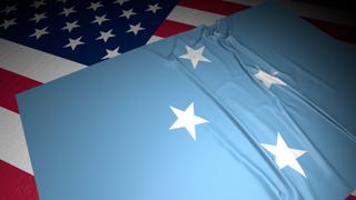 Federated-States-of-Micronesia National Flag, A flag placed on top of an American flag on a desk in a dark space