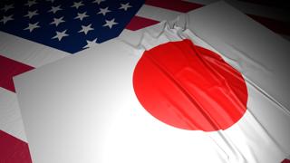 Japan National Flag, A flag placed on top of an American flag on a desk in a dark space