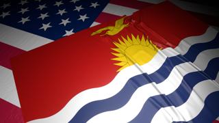 Kiribati National Flag, A flag placed on top of an American flag on a desk in a dark space