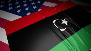 Libya National Flag, A flag placed on top of an American flag on a desk in a dark space