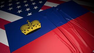 Liechtenstein National Flag, A flag placed on top of an American flag on a desk in a dark space