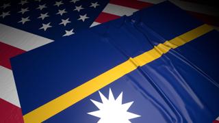 Nauru National Flag, A flag placed on top of an American flag on a desk in a dark space