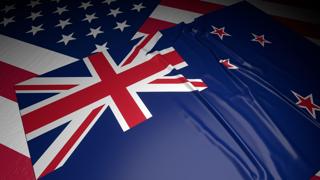 New-Zealand National Flag, A flag placed on top of an American flag on a desk in a dark space