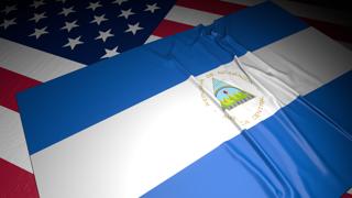 Nicaragua National Flag, A flag placed on top of an American flag on a desk in a dark space