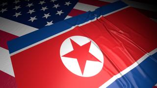 North-Korea National Flag, A flag placed on top of an American flag on a desk in a dark space