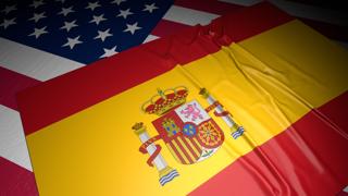 Spain National Flag, A flag placed on top of an American flag on a desk in a dark space