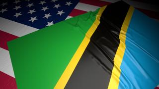 Tanzania National Flag, A flag placed on top of an American flag on a desk in a dark space