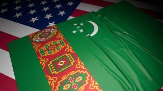 Turkmenistan National Flag, A flag placed on top of an American flag on a desk in a dark space