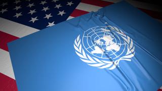 UN National Flag, A flag placed on top of an American flag on a desk in a dark space