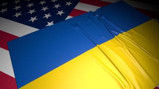 Ukraine National Flag, A flag placed on top of an American flag on a desk in a dark space