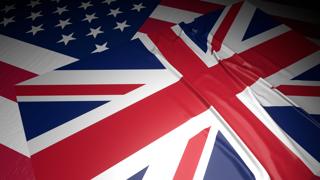 United-Kingdom National Flag, A flag placed on top of an American flag on a desk in a dark space