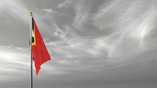 East-Timor National Flag, The national flag and flagpole visible from afar against a black and white sky background