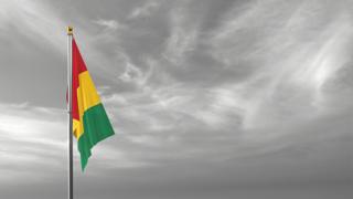 Guinea National Flag, The national flag and flagpole visible from afar against a black and white sky background