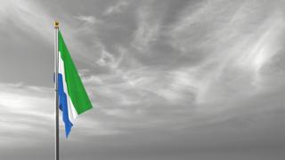 Sierra-Leone National Flag, The national flag and flagpole visible from afar against a black and white sky background