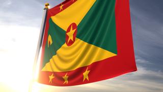 Grenada National Flag, A fluttering flag and flagpole seen up close against a dark blue sky