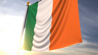 Ireland National Flag, A fluttering flag and flagpole seen up close against a dark blue sky