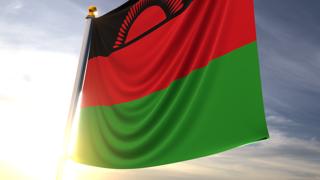 Malawi National Flag, A fluttering flag and flagpole seen up close against a dark blue sky