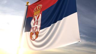 Serbia National Flag, A fluttering flag and flagpole seen up close against a dark blue sky