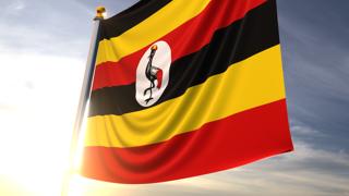 Uganda National Flag, A fluttering flag and flagpole seen up close against a dark blue sky